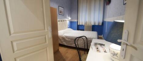 Una habitación pequeña y funcional con cama, escritorio y silla.