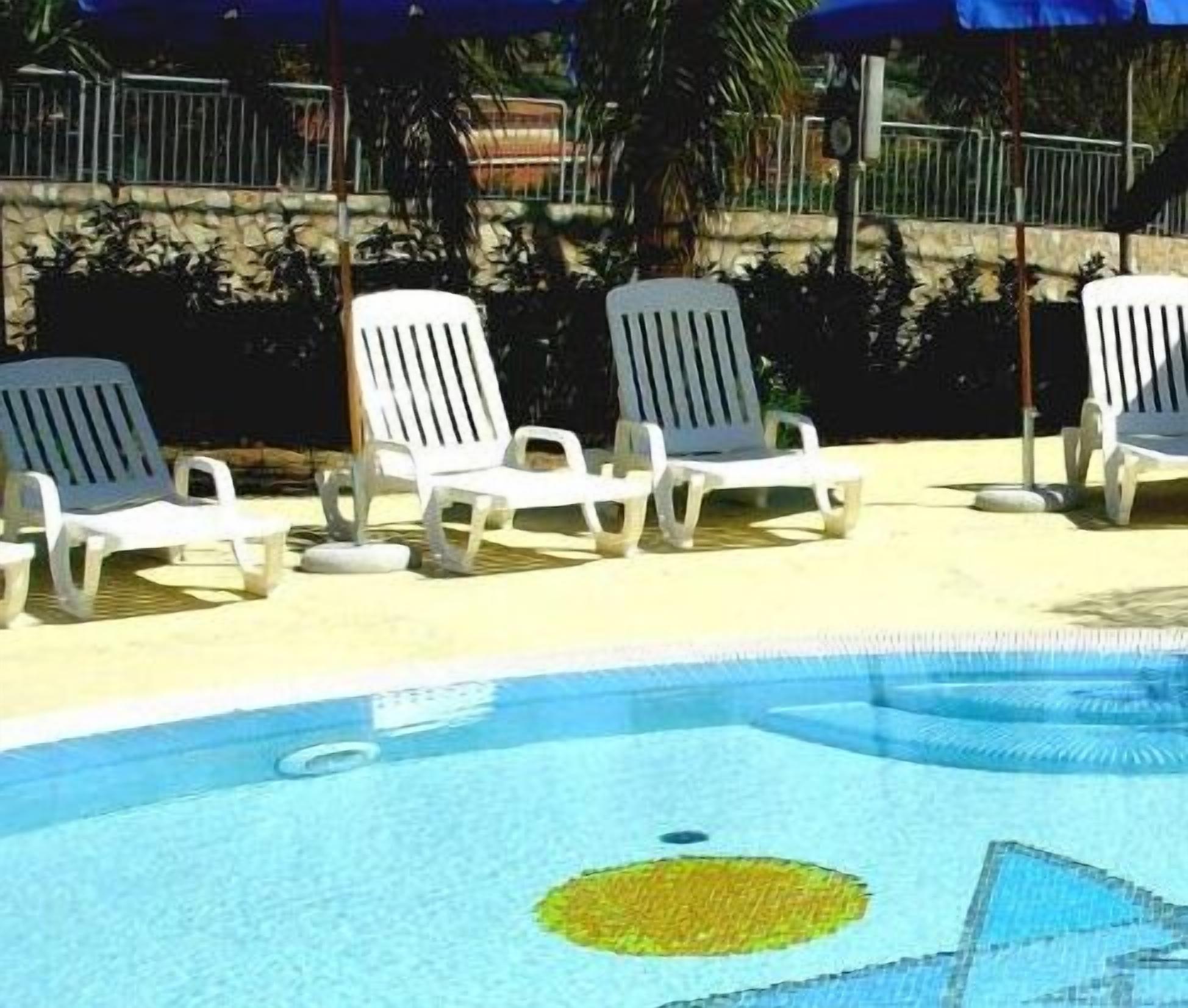 A pool area with white lounge chairs and a blue pool.