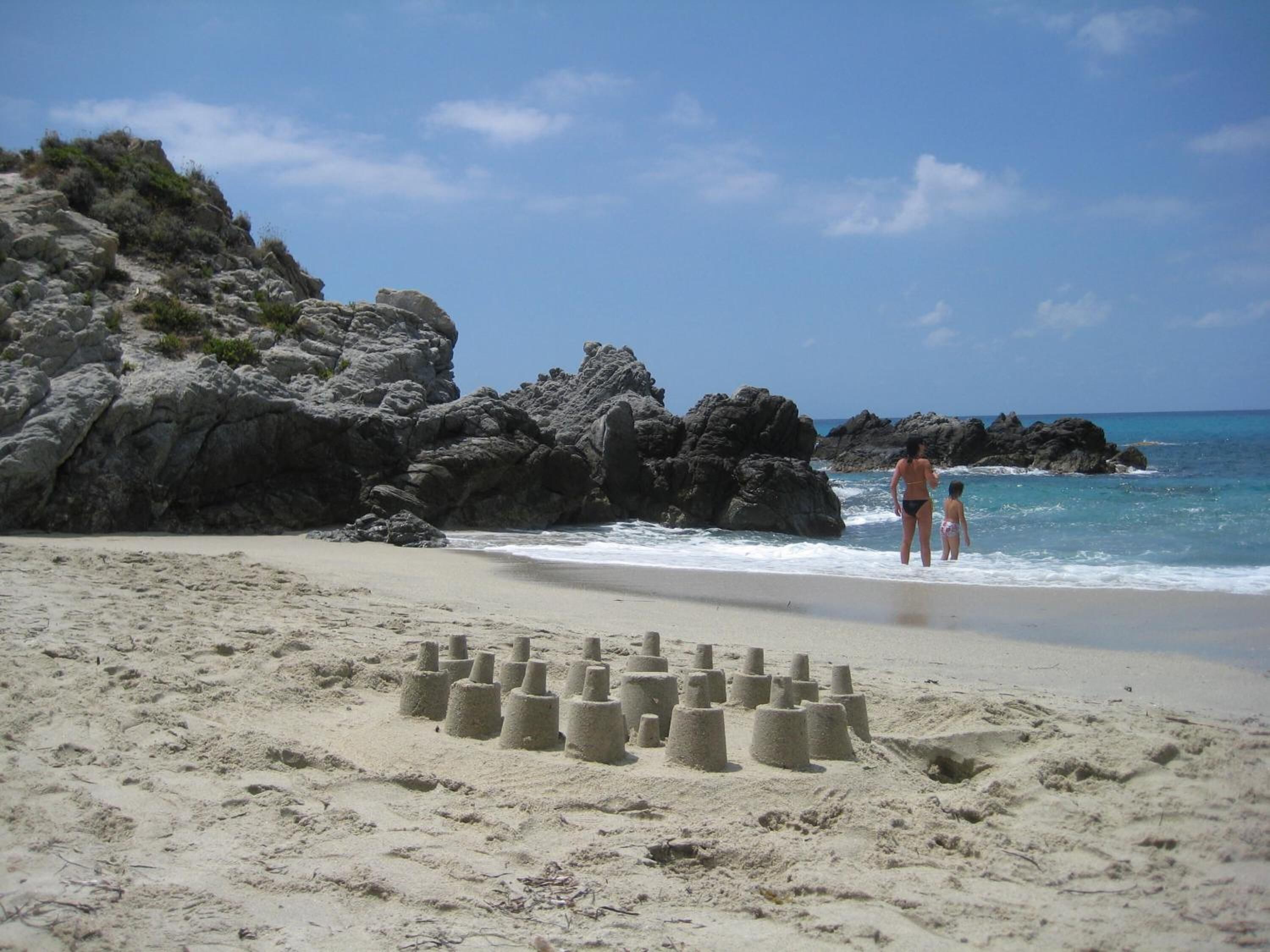A sandy beach with rocky outcrops and a clear sky.