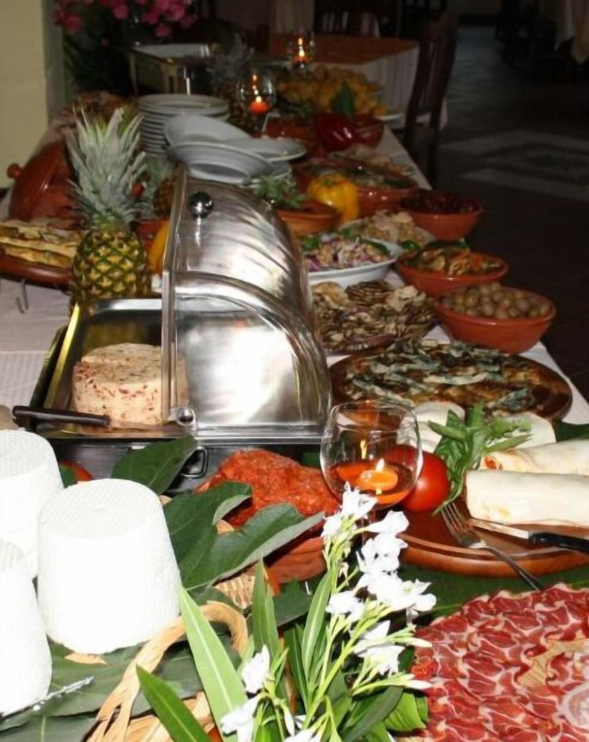 A buffet table with various food items, including a meat platter, salads, and tropical fruits.