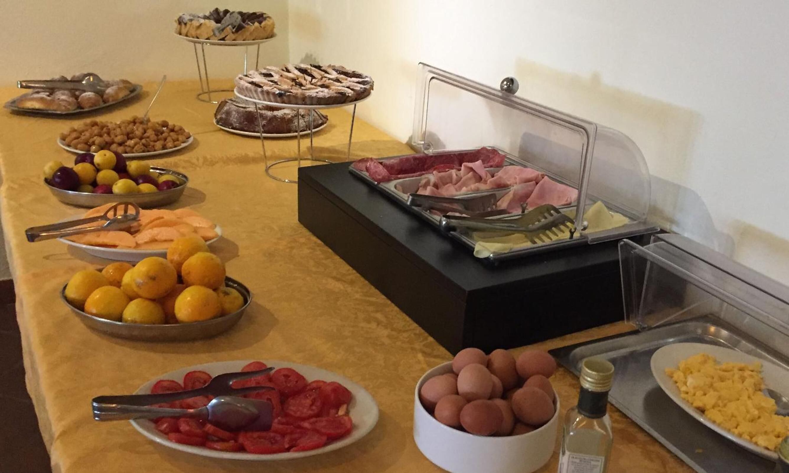 Een buffet met diverse gerechtjes, zoals fruit, vleeswaren en gebak.