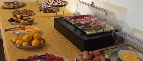 Een buffet met diverse gerechtjes, zoals fruit, vleeswaren en gebak.
