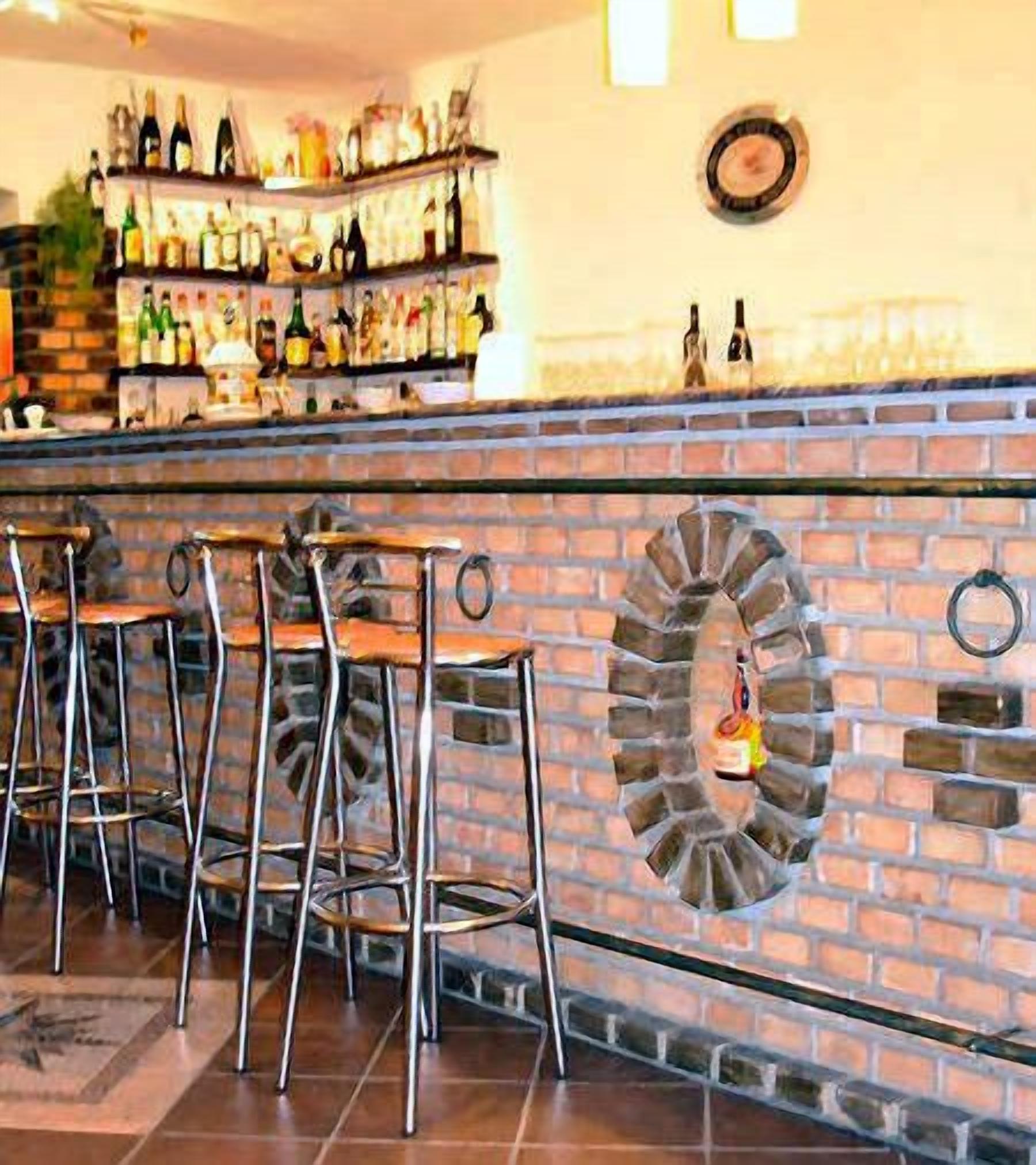 Un espace bar avec des tabourets et un mur en briques orné d’un motif circulaire.