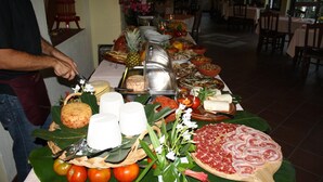 Una mesa de buffet con diferentes alimentos y una persona sirviendo.