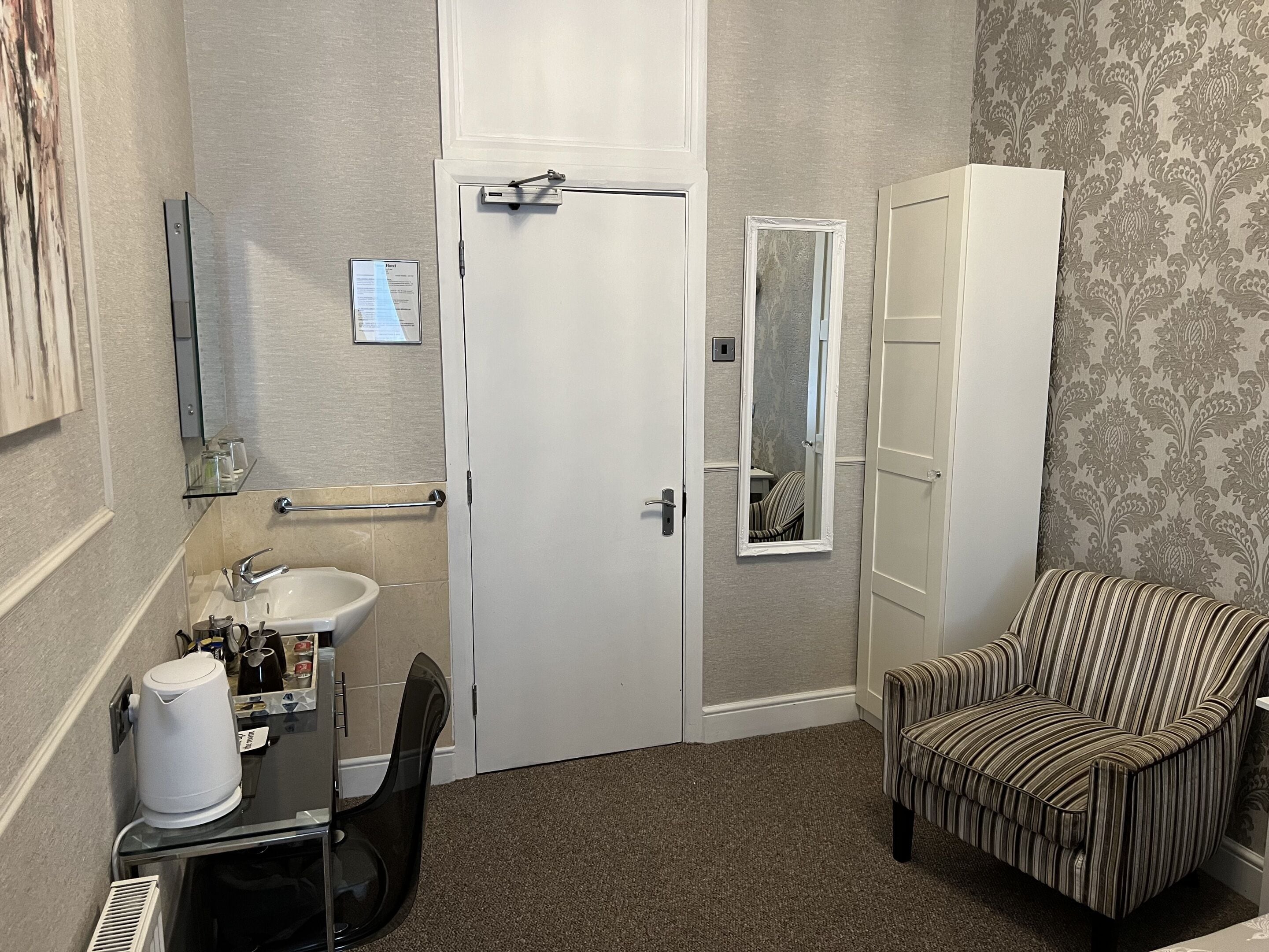 A compact bathroom with a toilet, sink, and a chair.