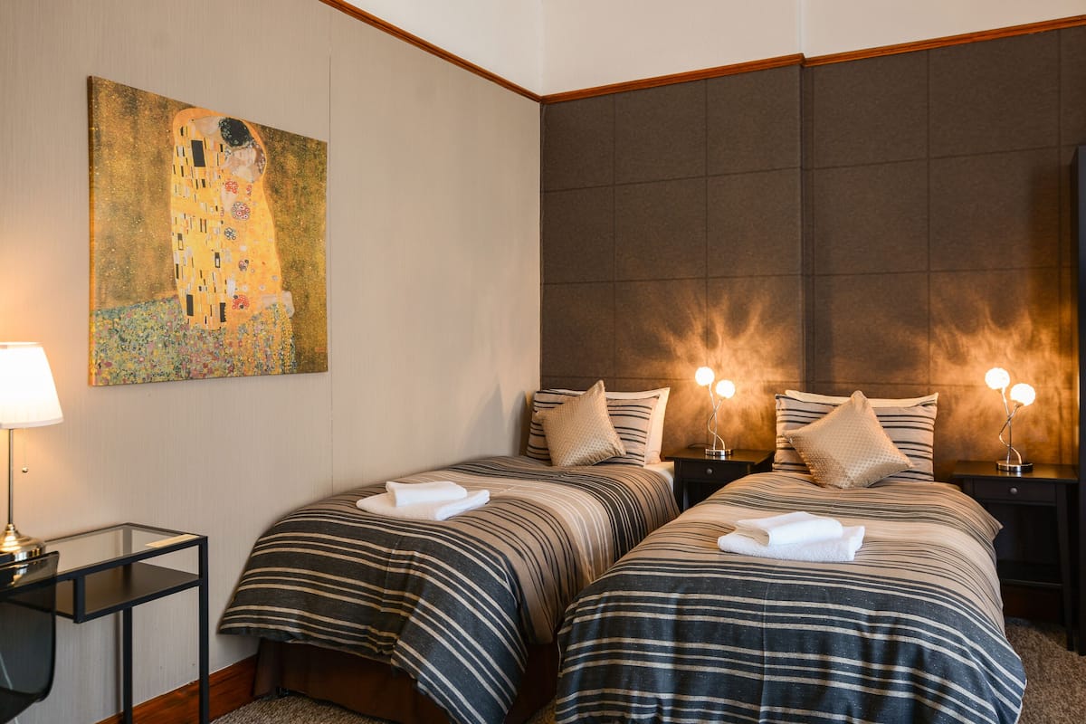 Habitación de hotel con dos camas, un cuadro en la pared y lámparas de noche.