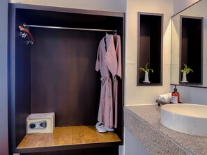 A modern bathroom with a wooden vanity, a towel rack with a robe, a radio, and a mirror with a plant. - Eastern Grand Palace (Pattaya)