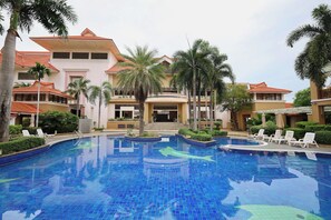 A swimming pool with tiled blue floor, surrounded by palm trees and lounge chairs. - Eastern Grand Palace (Pattaya)