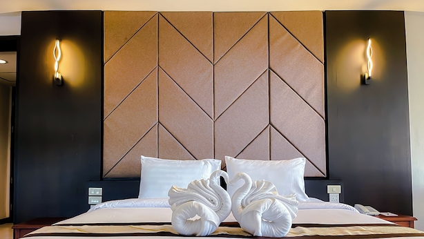 Habitación de hotel con una cama grande, dos lámparas de pared y un cabecero con diseño geométrico.