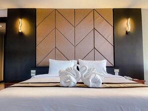 A hotel room with a large bed, two wall-mounted lights, and a geometric-patterned headboard.