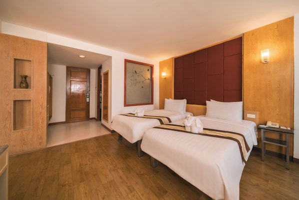 A hotel room with two beds, wooden flooring, a large wall-mounted artwork, and a wooden panel wall.