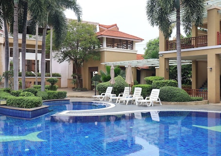 Una piscina al aire libre, sombrillas, sillones reclinables de piscina