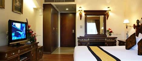 Una habitación de hotel con una cama grande, televisor, cómoda y espejo.