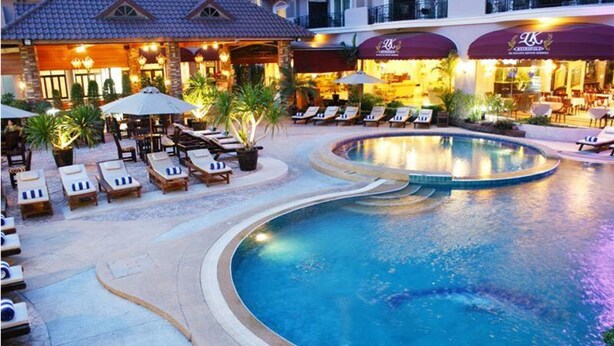 Een hotel met een zwembad, lounge stoelen en terrassen.