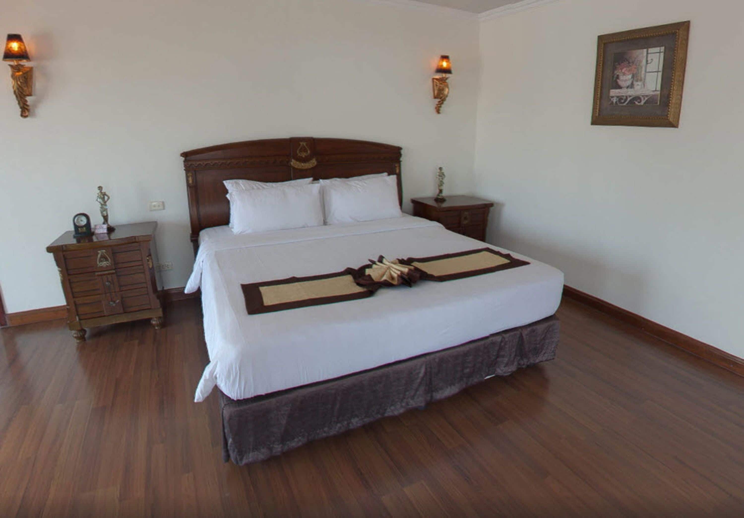 A neatly made bed with a wooden headboard, two bedside tables, and wall-mounted lamps.