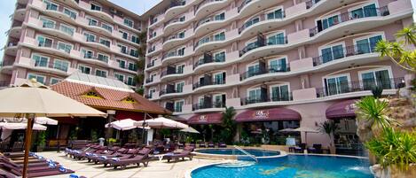 A hotel with multiple balconies, a swimming pool, and sun loungers.