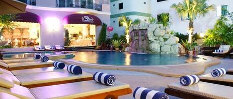 A pool area with lounge chairs and a restaurant in the background.