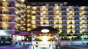 Een meerlaags hotel met balkons, een fontein in het midden en een bord met de tekst 'METROPOLIS'.