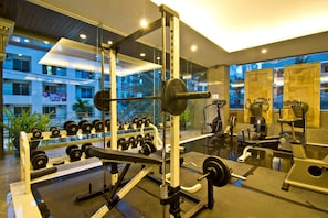 Une salle de sport équipée de matériel de musculation, d’un banc et d’haltères.