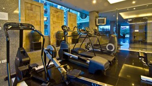 A gym with treadmills, elliptical machines, and weight machines. - LK Royal Suite Pattaya (Pattaya)
