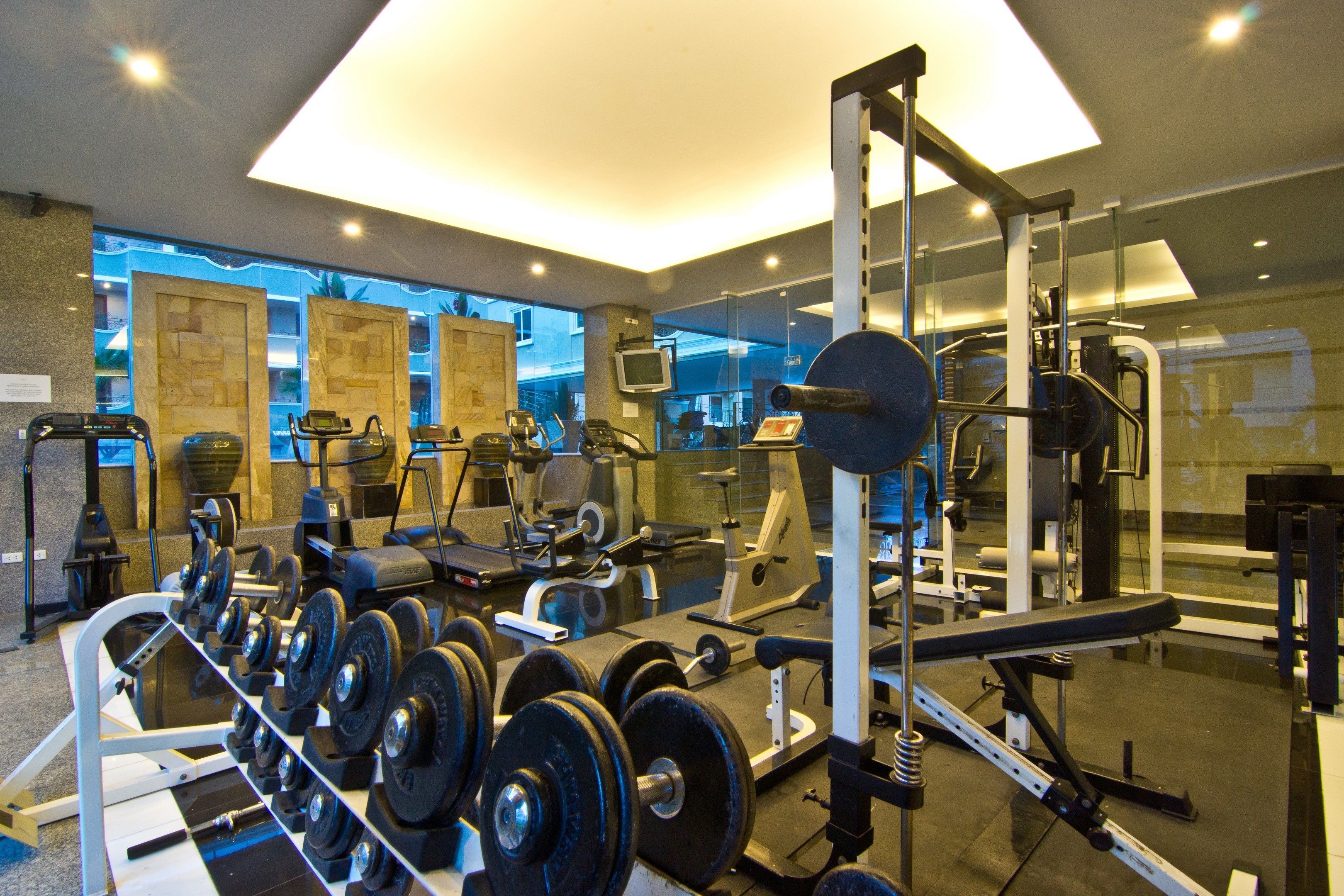 Ein Fitnessstudio mit verschiedenen Trainingsgeräten, darunter Laufbänder, Kraftgeräte und Kurzhanteln.