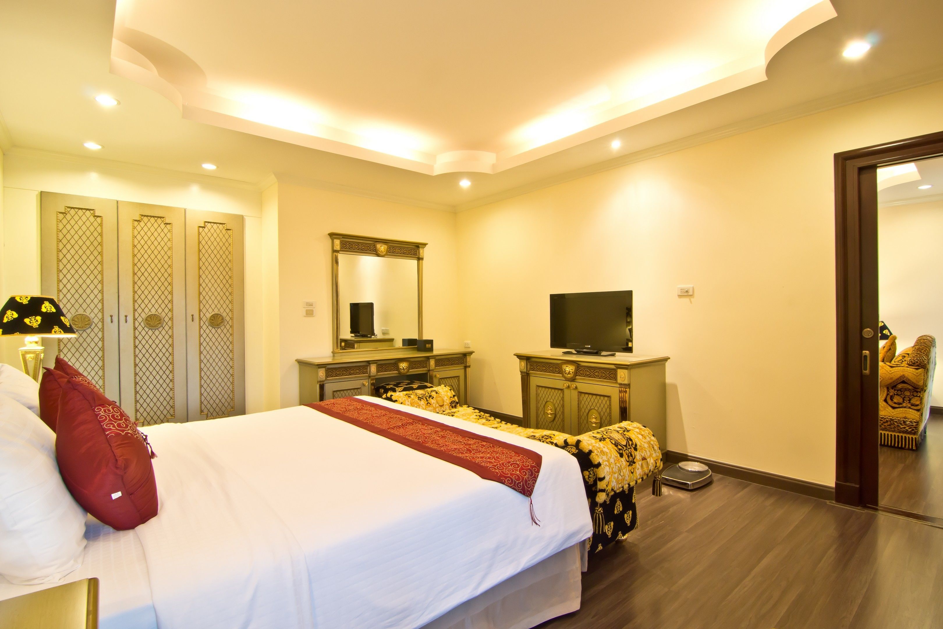 A hotel room with a bed, a TV, a wardrobe, and a mirror.