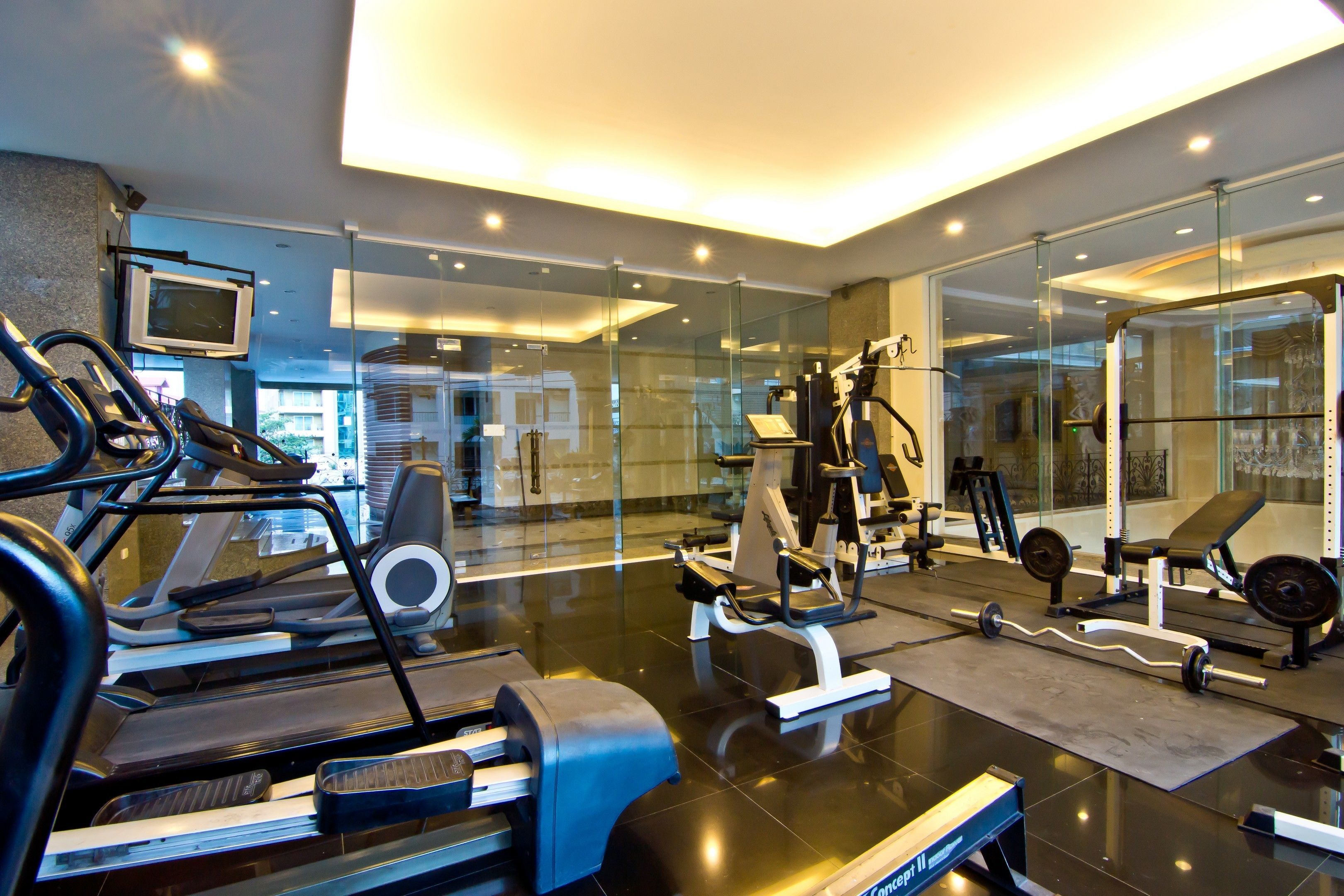 Ein modernes Fitnessstudio mit Laufbändern, Kraftgeräten und einer Spiegelwand.
