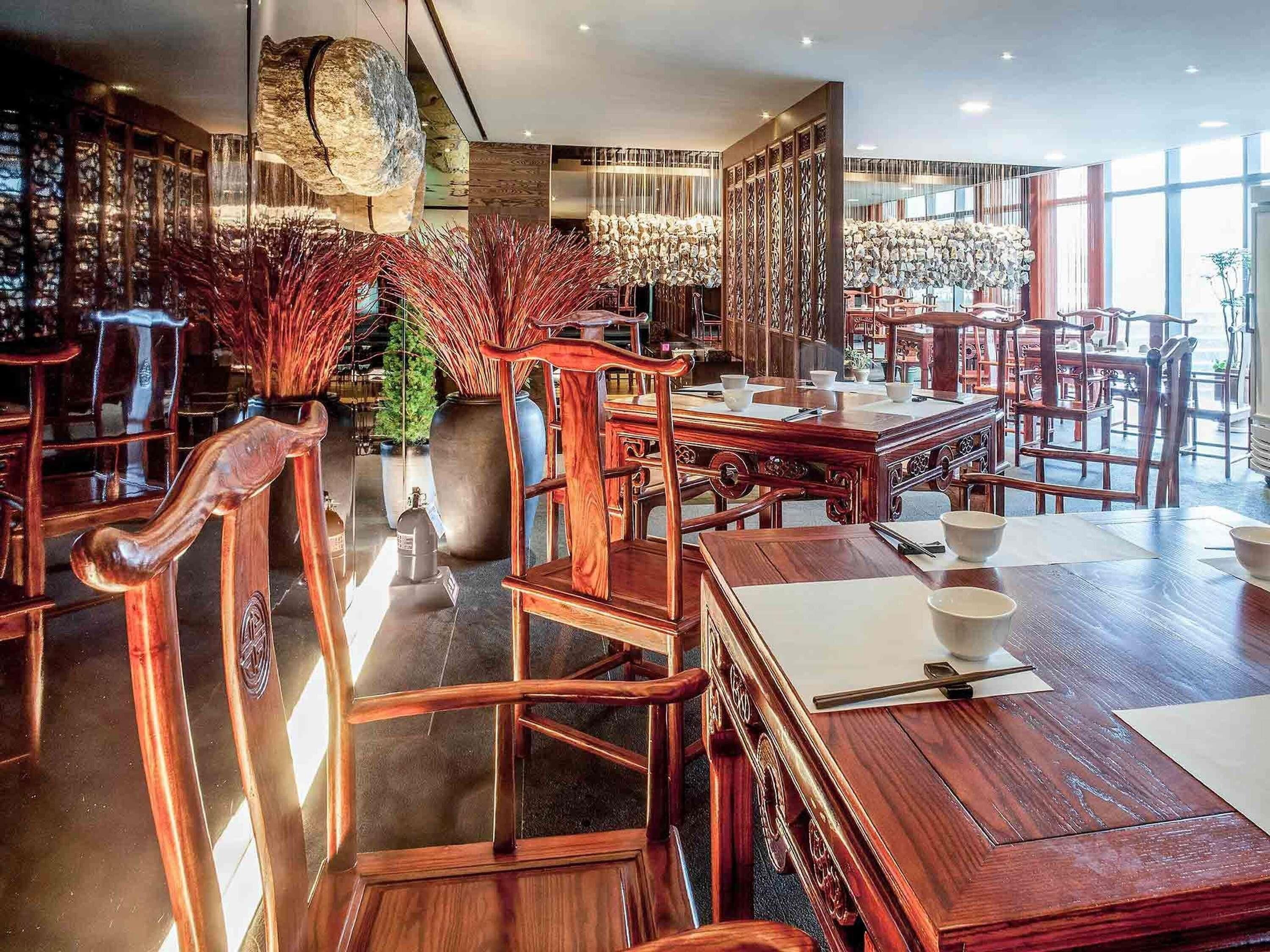 A traditional-style restaurant with wooden furniture, large windows, and decorative elements.