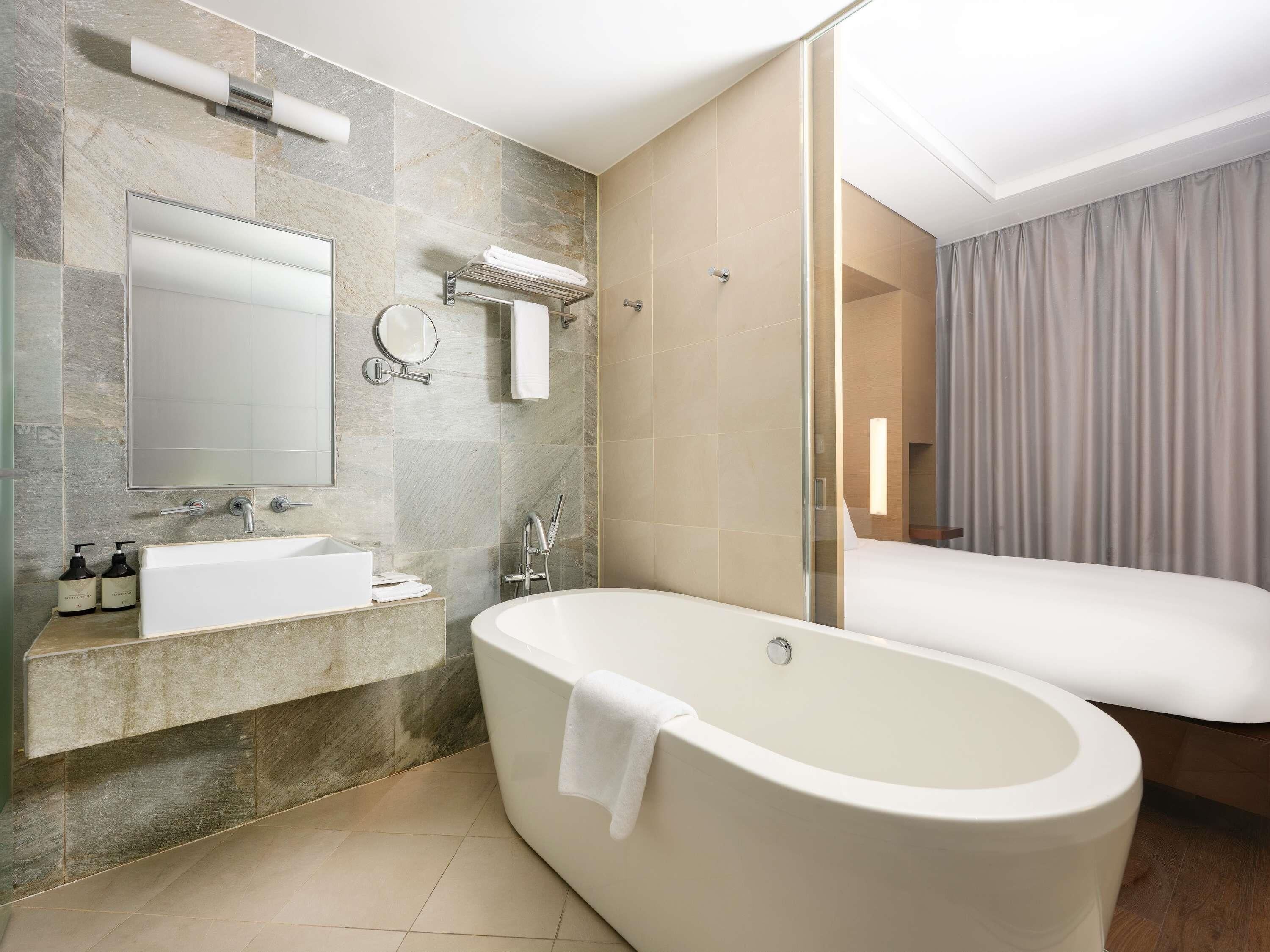 A modern bathroom with a freestanding bathtub, a vanity with a mirror, and a shower area.
