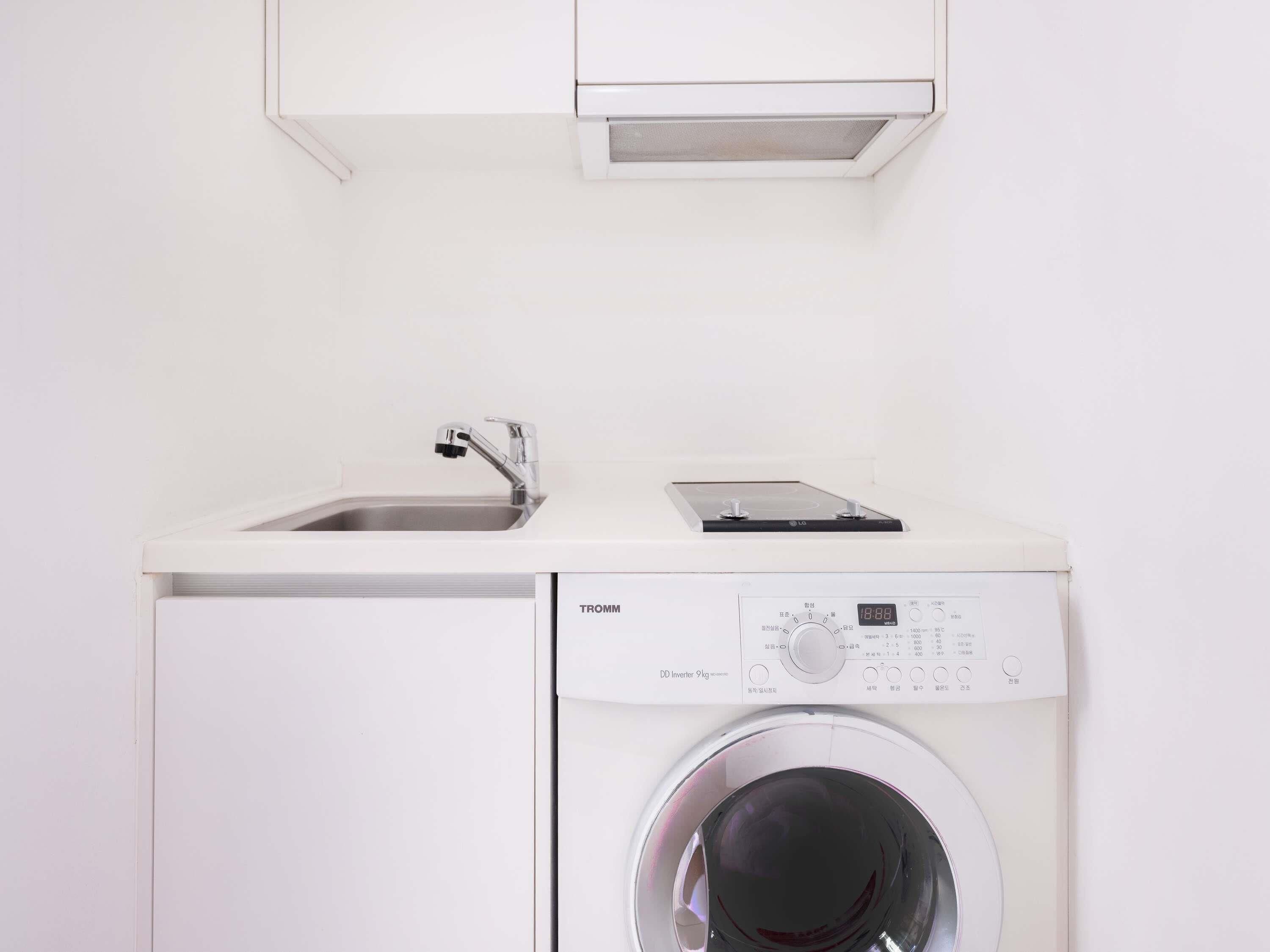 A compact washer and dryer unit with a control panel, a sink, and a cabinet above.