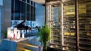 A grand piano, a glass display case with shoes, and a marble reception area with candles. - Grand Mercure Ambassador Changwon (Changwon)