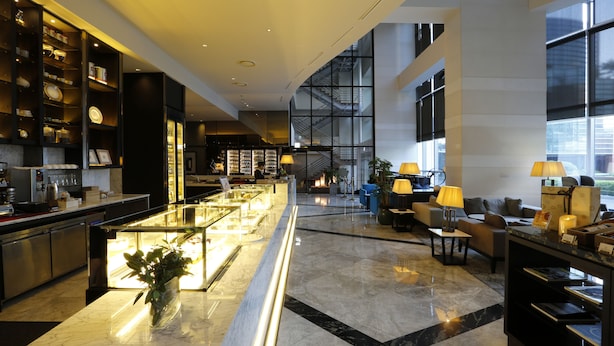 A modern hotel lobby with a marble reception desk, seating area with lamps, and large windows offering views. - Grand Mercure Ambassador Changwon (Changwon)