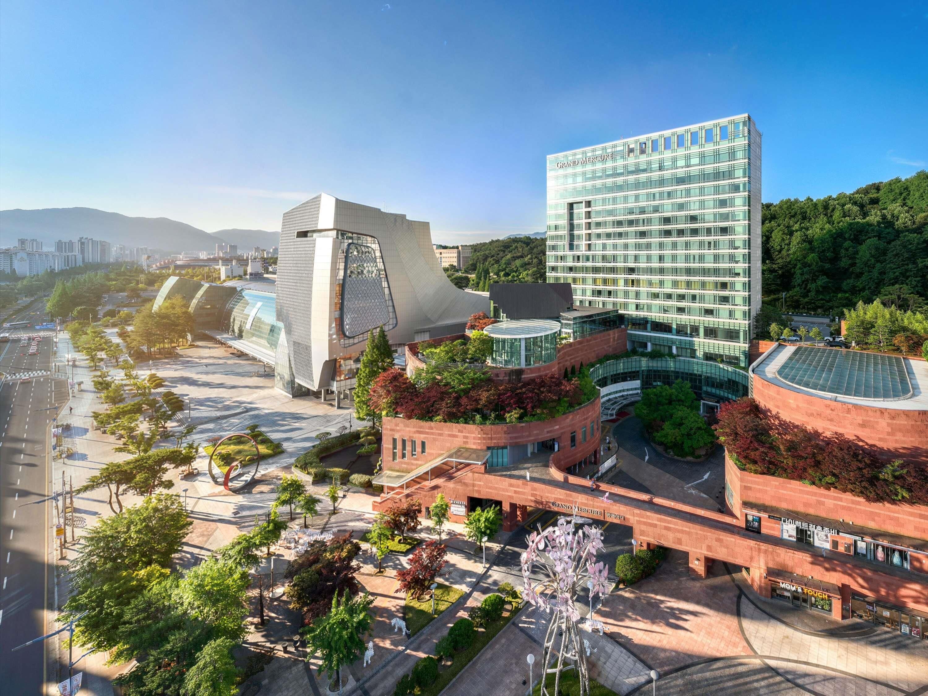 A modern building complex with a glass facade, a distinctive curved structure, and a central atrium.