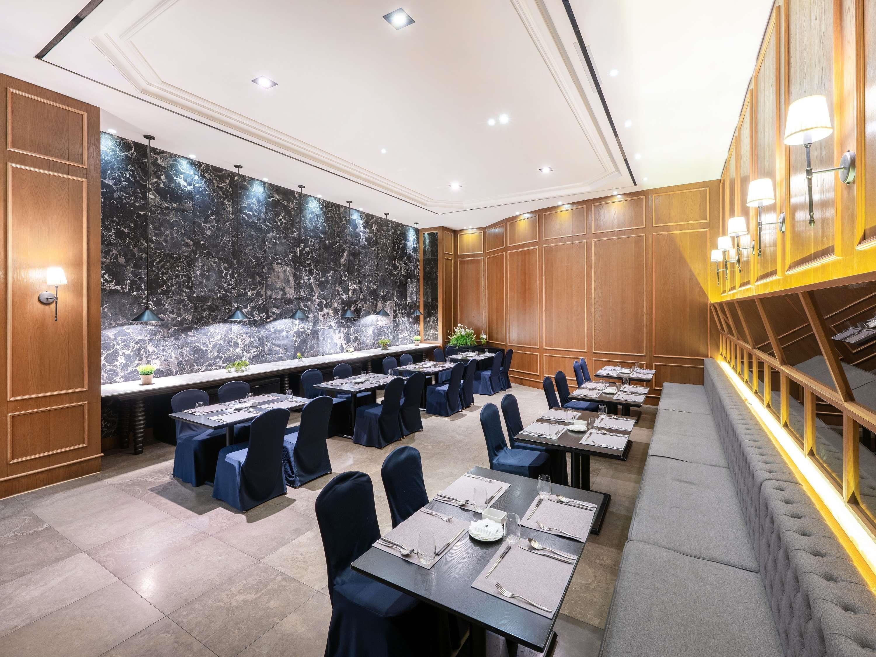 A conference room with a long table, multiple chairs, and a marble wall.