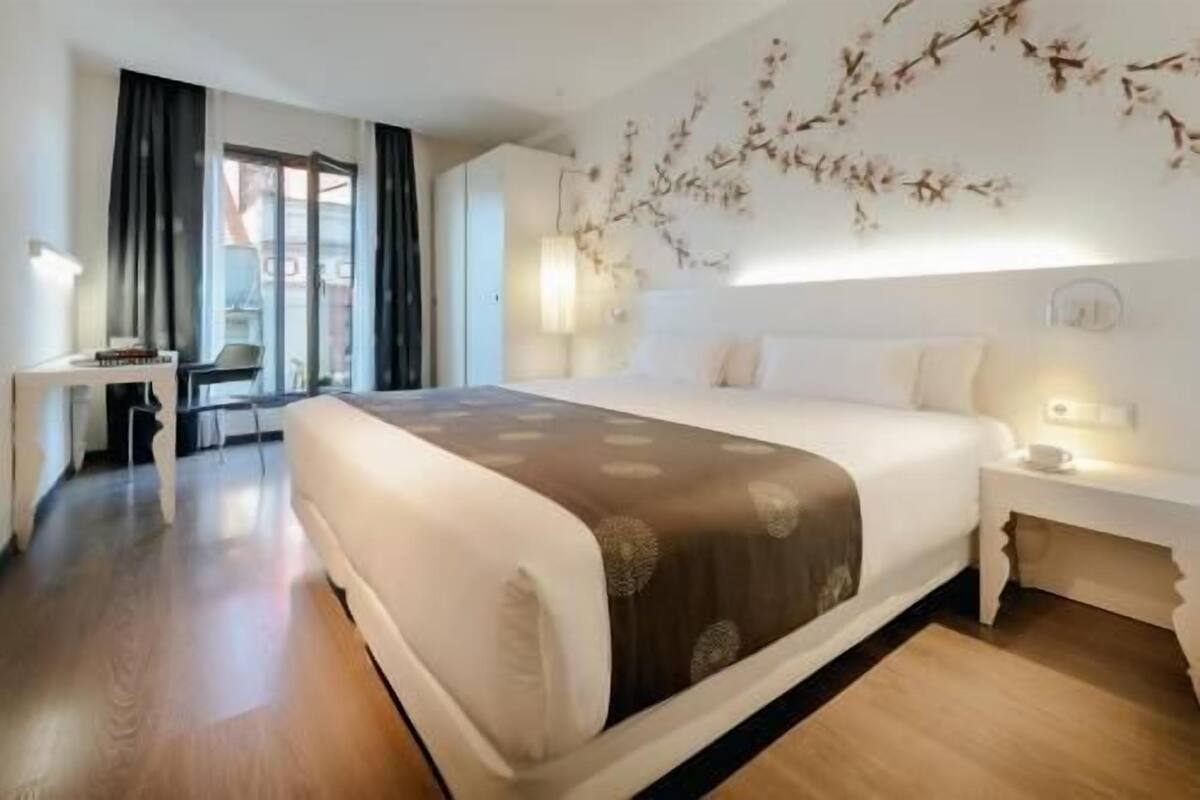 A hotel room with a large bed, a desk, and a chair.