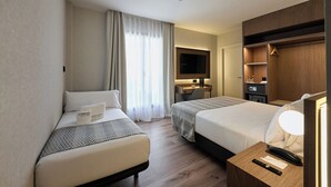 Habitación de hotel con dos camas, un escritorio, un televisor y un armario.