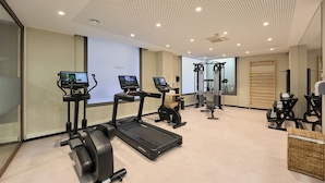 Un gimnasio con cintas de correr, elípticas y un espejo grande.