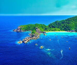 A coastal landscape with rocky outcrops, clear blue waters, and a sandy beach. - Andatel Grandé Patong Phuket (Patong)