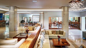 Un hall d’entrée spacieux, avec un long banc en bois, un canapé et une table basse. On y trouve plusieurs espaces repas, avec des tables et des chaises.