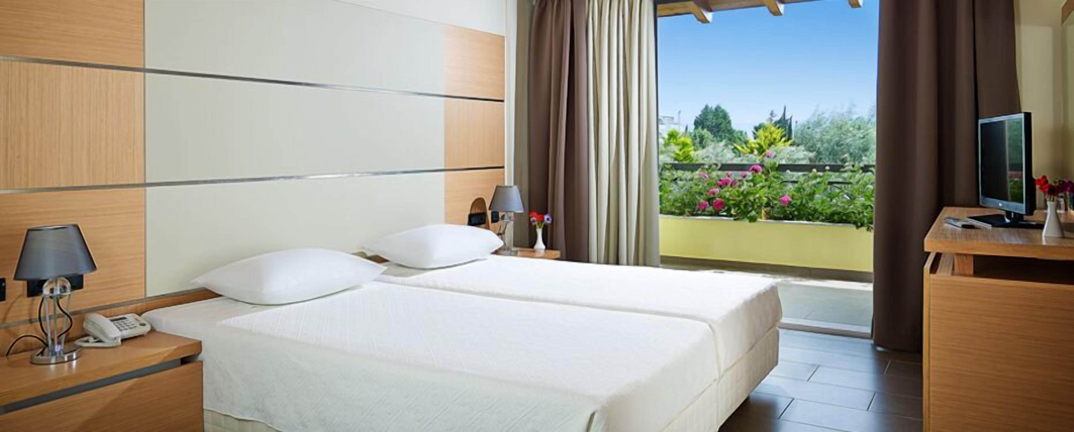 A hotel room with two beds, a desk with a computer, a lamp, and a phone.