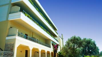 Un hotel de varios pisos con balcones, fachada de piedra y cielo azul despejado.