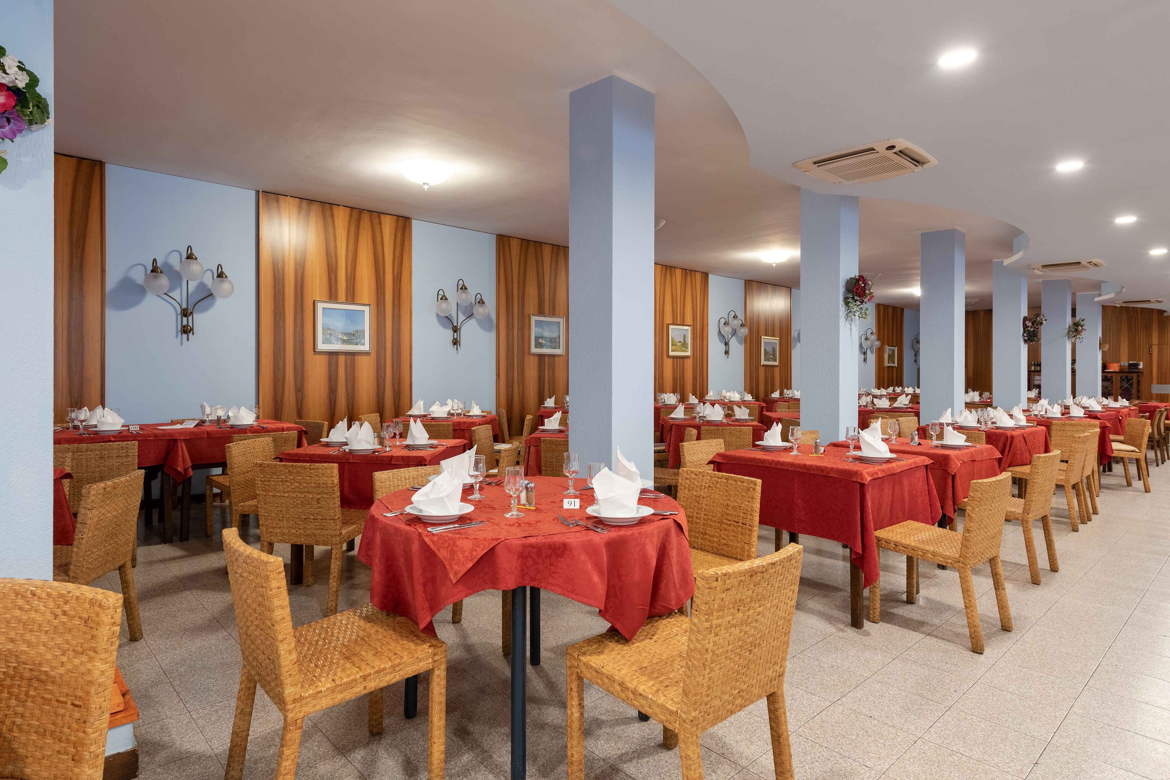 A dining area with multiple tables and chairs, each set with white napkins and silverware.