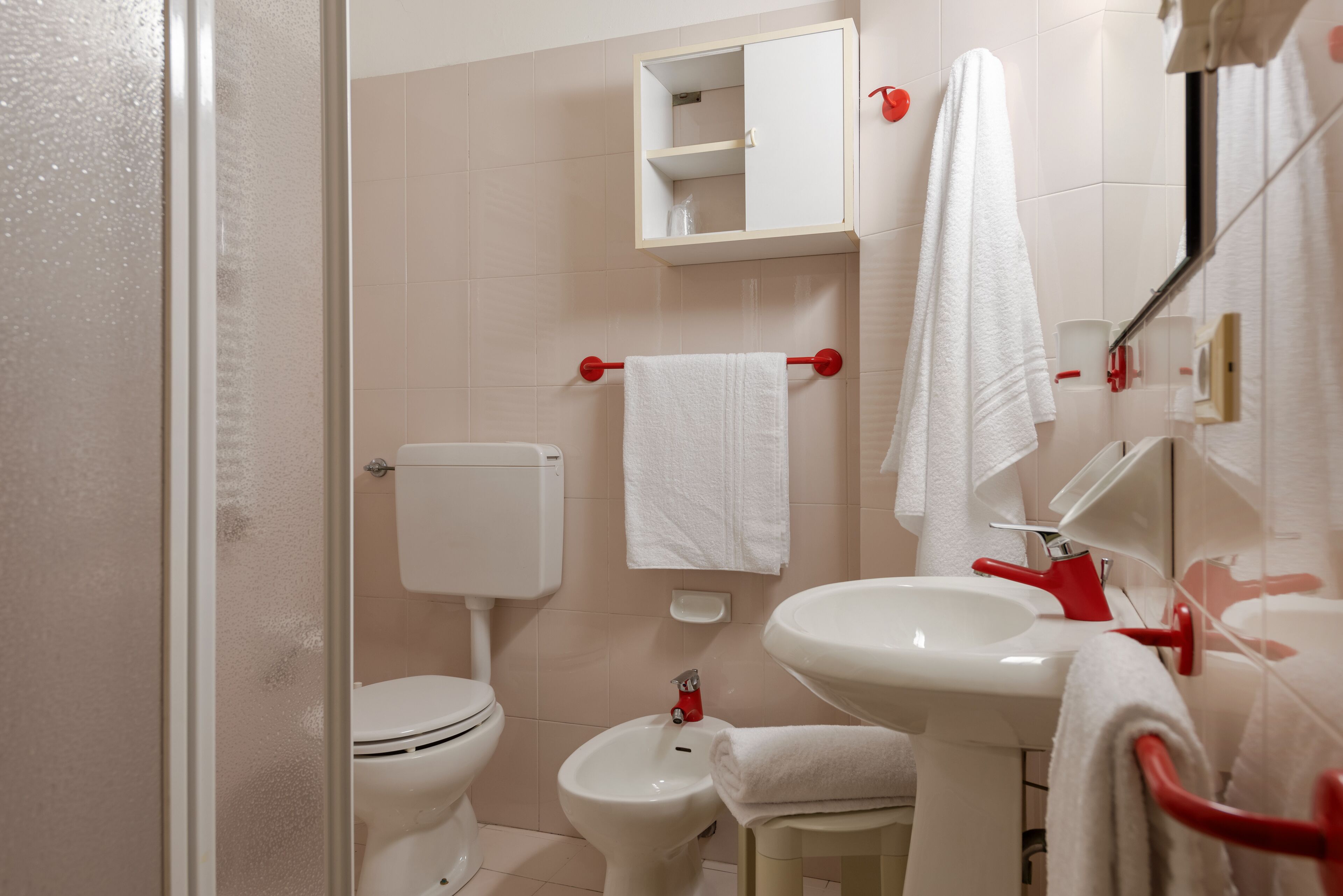 Une salle de bain comprenant des toilettes, un bidet, un lavabo et un meuble au-dessus du lavabo.