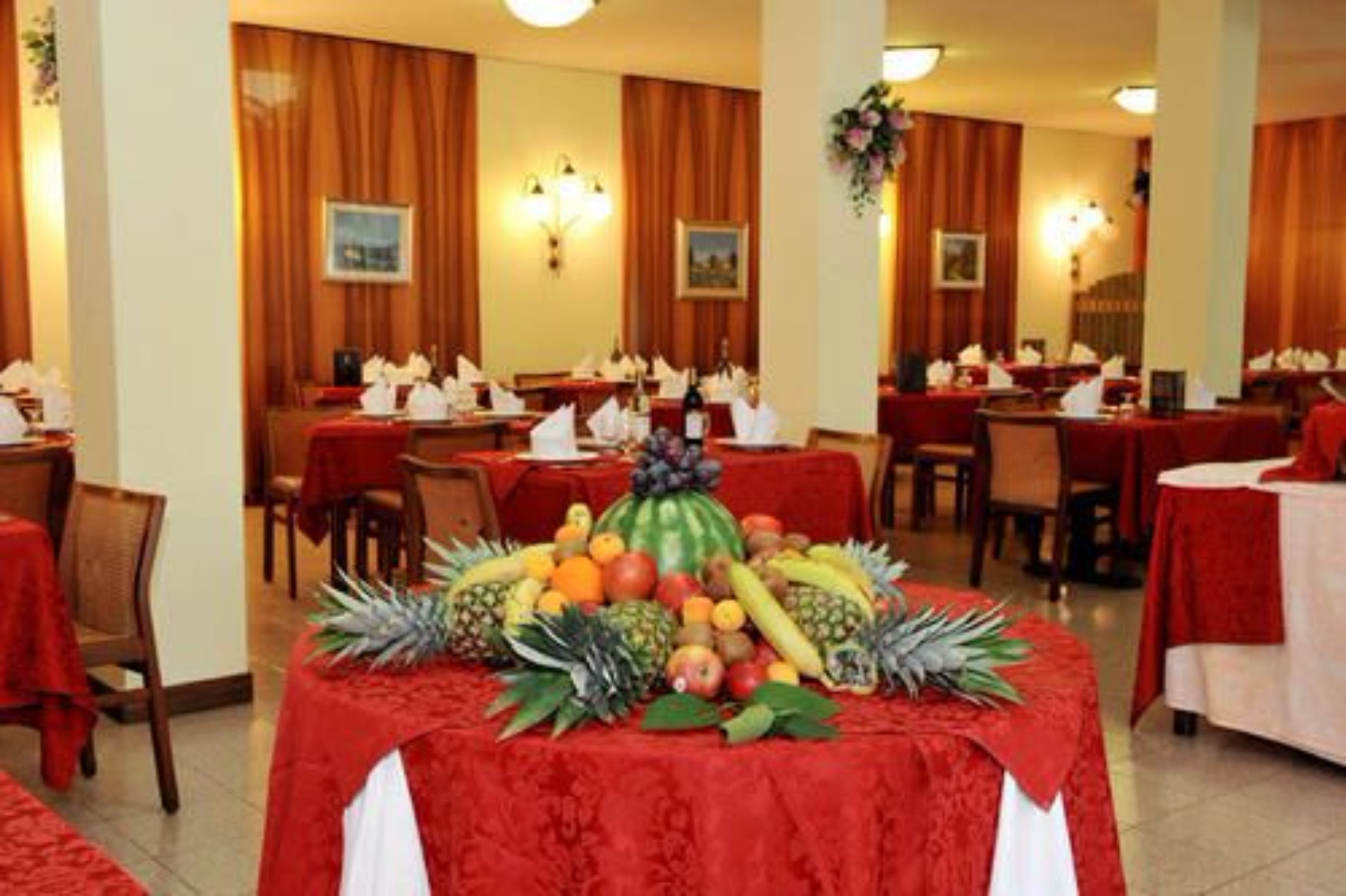 Ein Essbereich eines Hotels mit gedeckten Tischen und einer zentral platzierten Obstauslage.