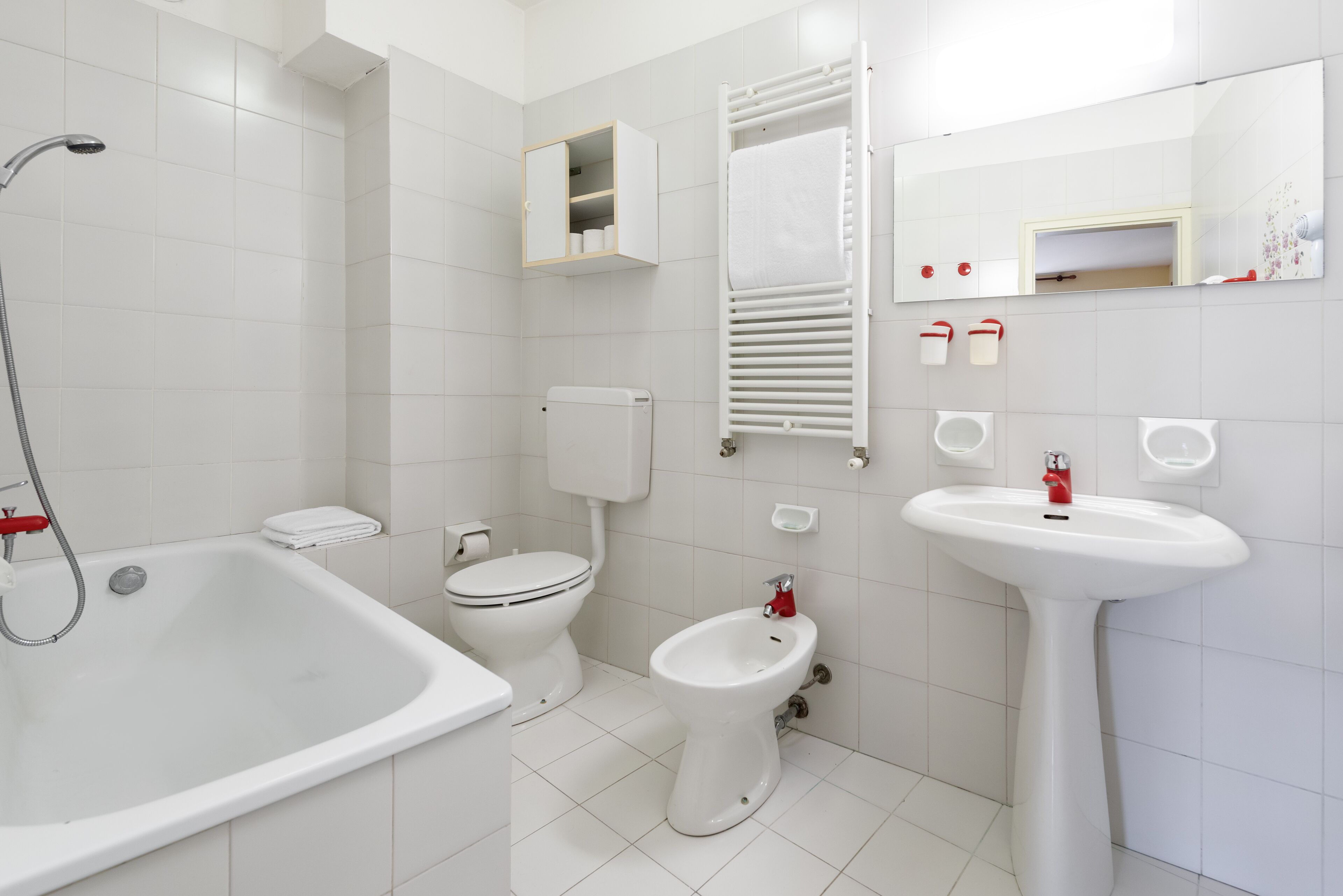 A modern bathroom with a bathtub, toilet, bidet, and sink.