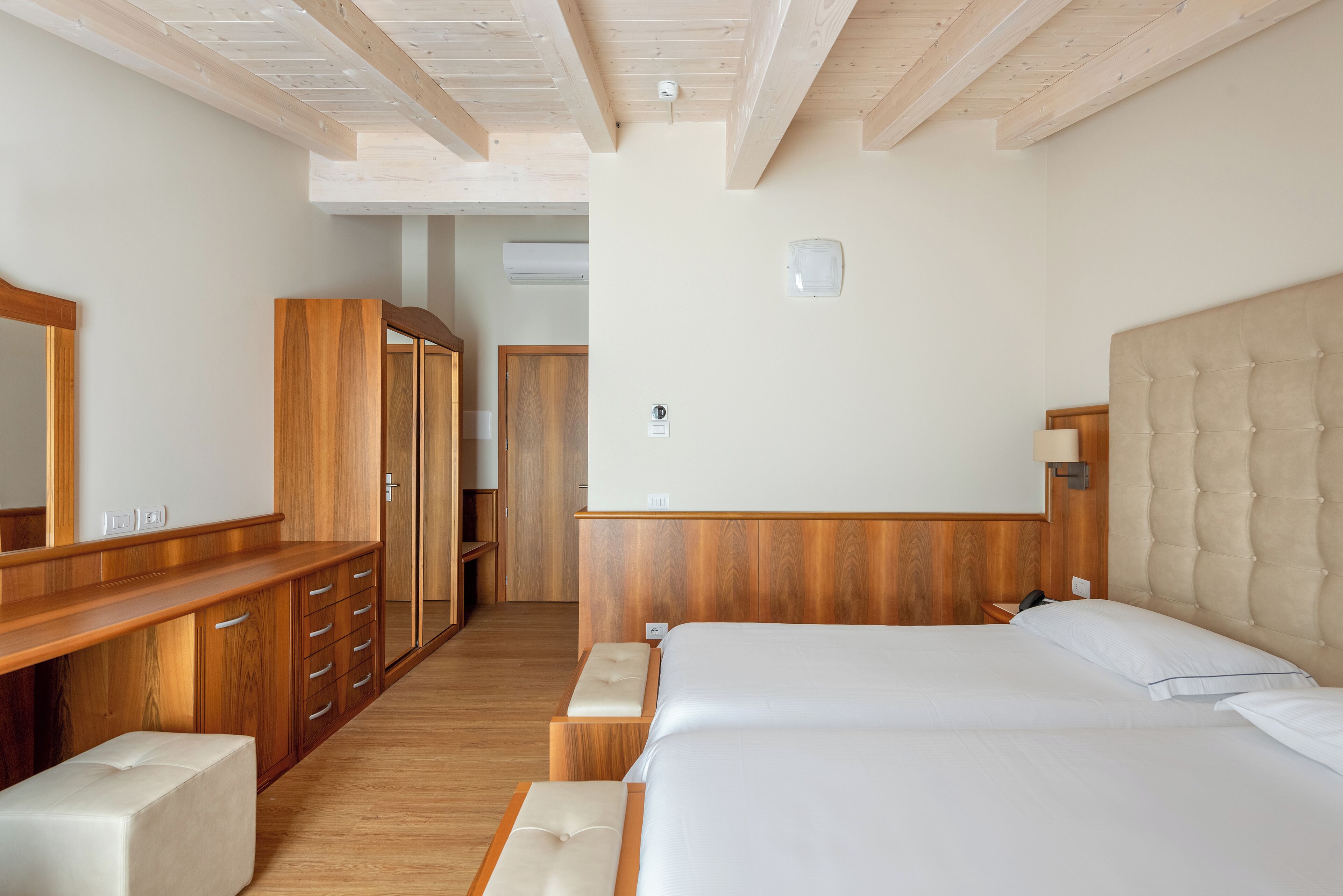 Een slaapkamer met een groot bed, een houten garderobe en een spiegel.