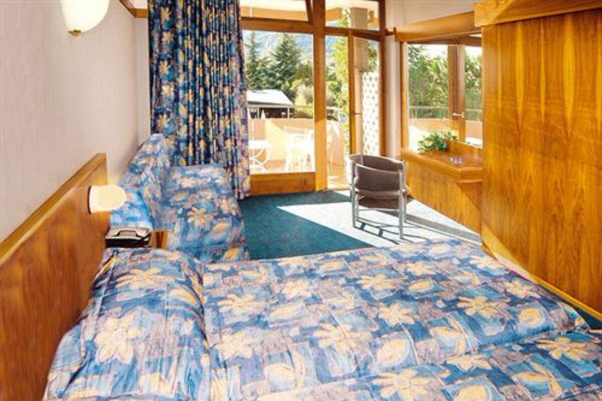 A room with a bed, a chair, and a view of the outdoors.