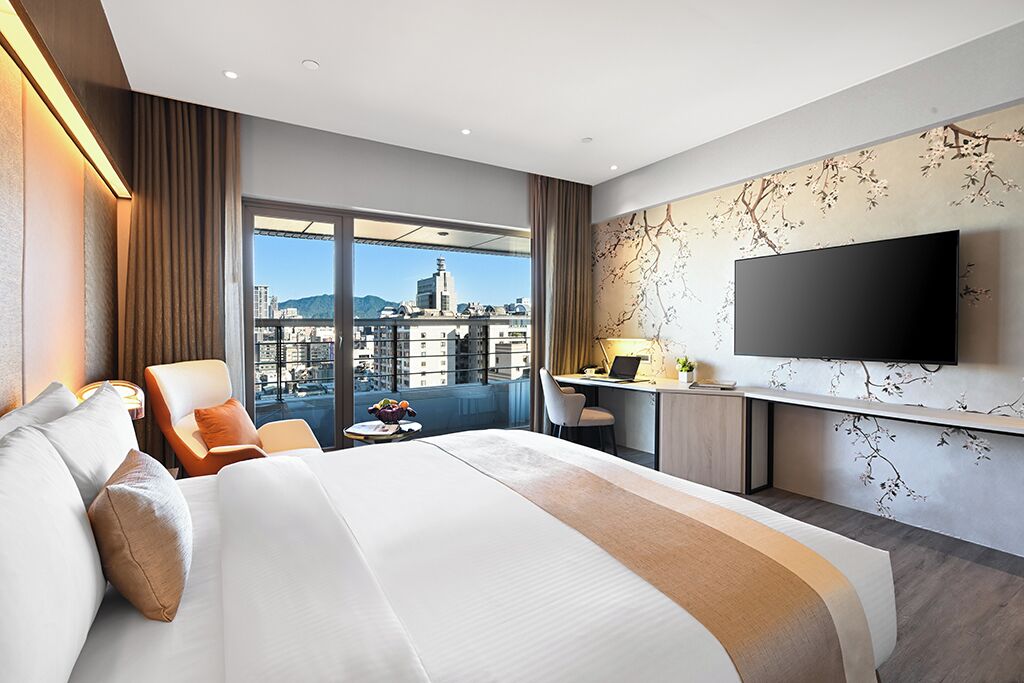 Une chambre d’hôtel moderne avec un grand lit, un bureau et une télévision.