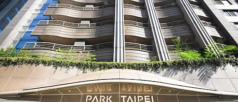 Un immeuble moderne de grande hauteur, avec une enseigne bien visible indiquant « Park Taipei » à l’entrée.