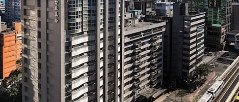 Un edificio de gran altura con varios pisos, un diseño arquitectónico moderno y un paseo peatonal a nivel de calle.